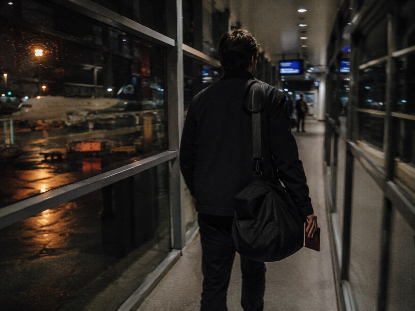Mann mit Reisepass am Flughafen-Gate bei Nacht